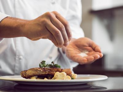 Chef che aggiunge sale a un piatto raffinato.