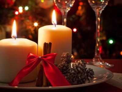 Candele natalizie con fiocchi rossi e calici sullo sfondo.