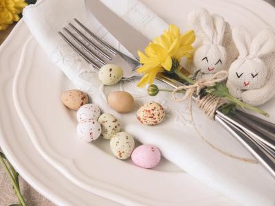 Tavola pasquale con uova colorate e decorazioni floreali.