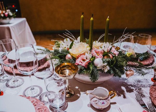 Tavola elegante con fiori, candele e bicchieri di cristallo.
