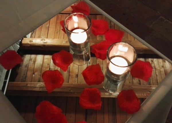 Candele e petali rossi su specchio, atmosfera romantica.
