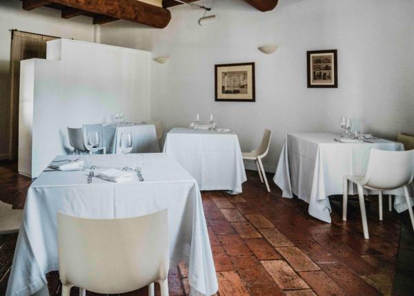 Ristorante elegante con tavoli apparecchiati e sedie bianche.
