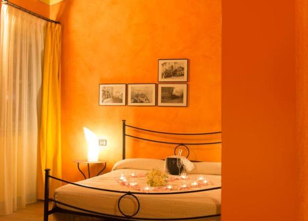 Camera accogliente con pareti arancioni e letto decorato con candele.