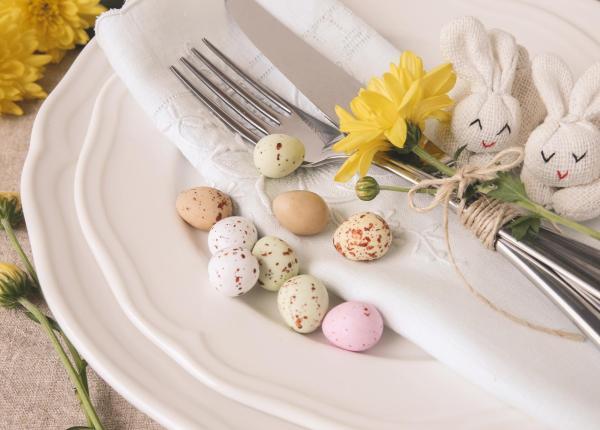 Tavola pasquale con uova colorate e decorazioni floreali.